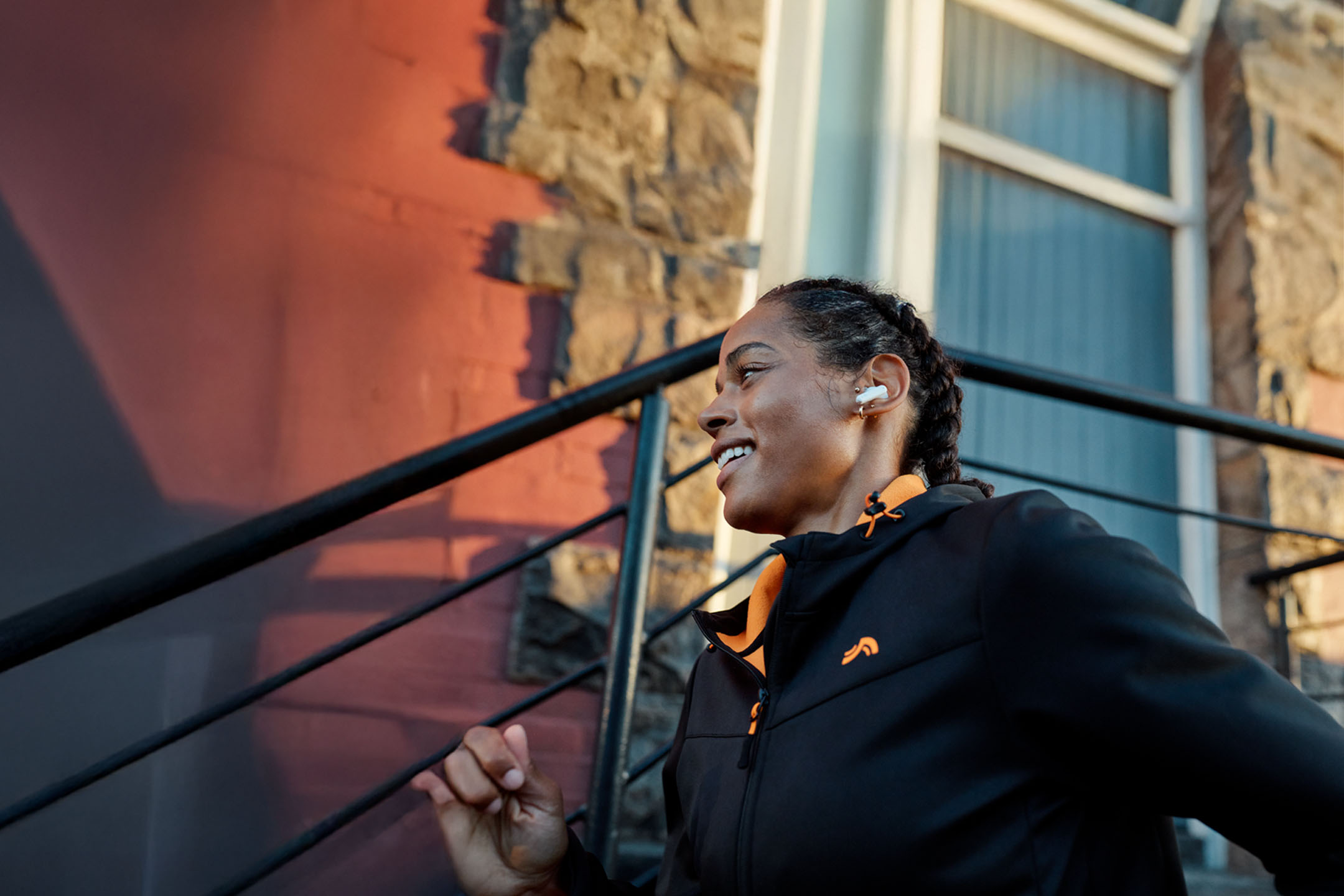 Sieviete skrien ar austiņām, ģērbta jakā.