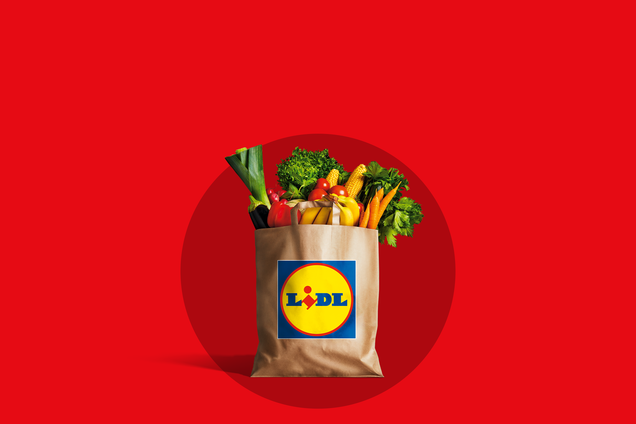 Lidl papīra maisiņš, pilns ar svaigiem dārzeņiem un augļiem, uz sarkana fona.