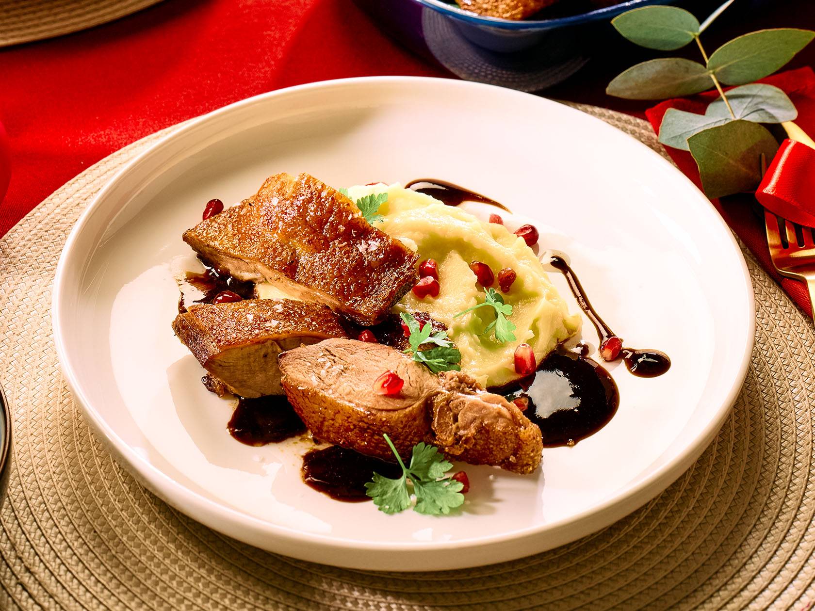 Pīles krūtiņa ar biezeni, granātābolu un mērci uz balta šķīvja.