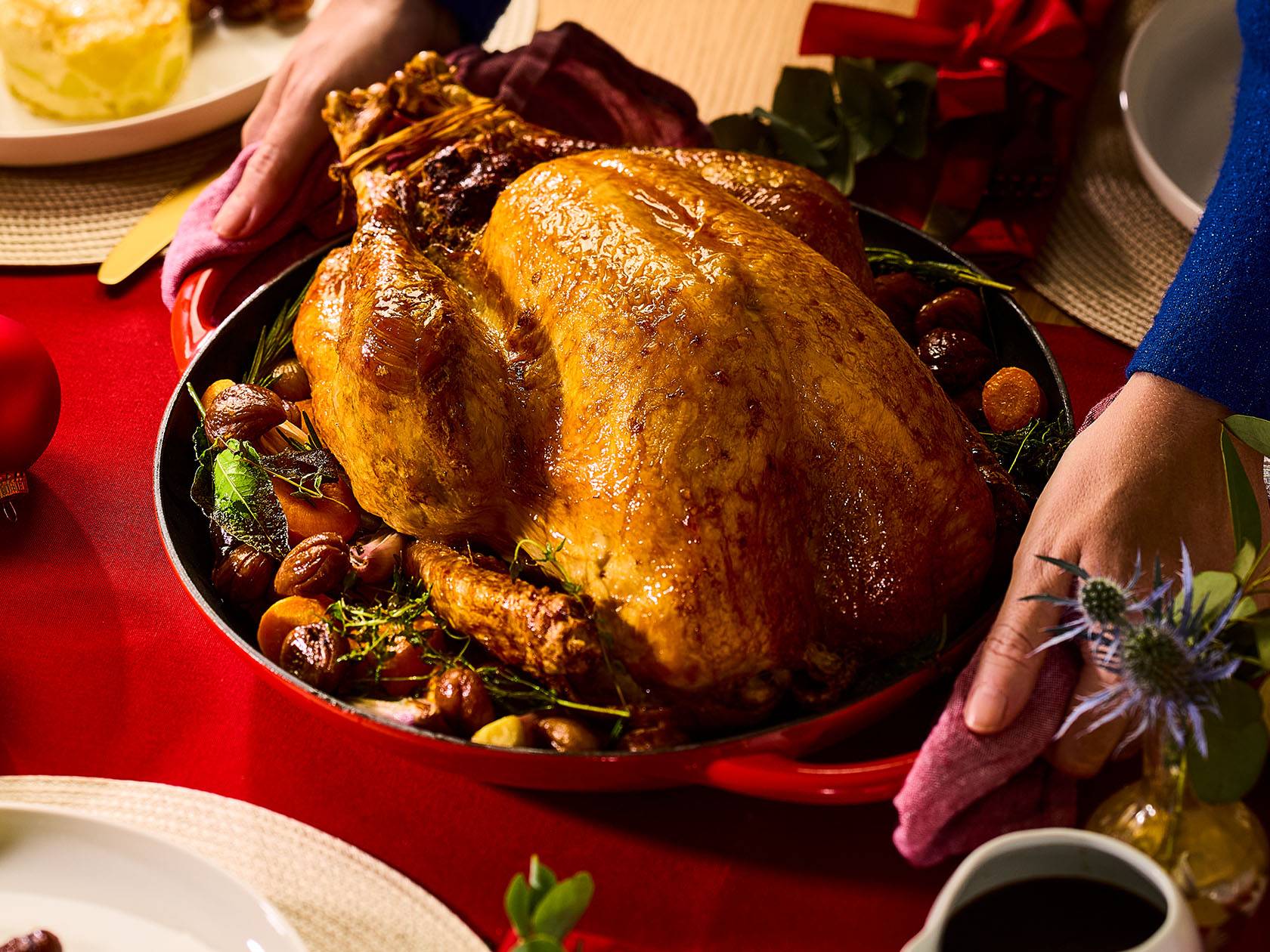 Ziemassvētku tītars ar dārzeņiem un kastaņiem uz sarkana galda.